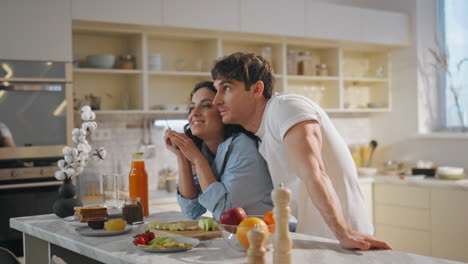 mujer disfrutando del desayuno hombre de pie en la cocina de la casa. pareja comiendo frutas frescas.