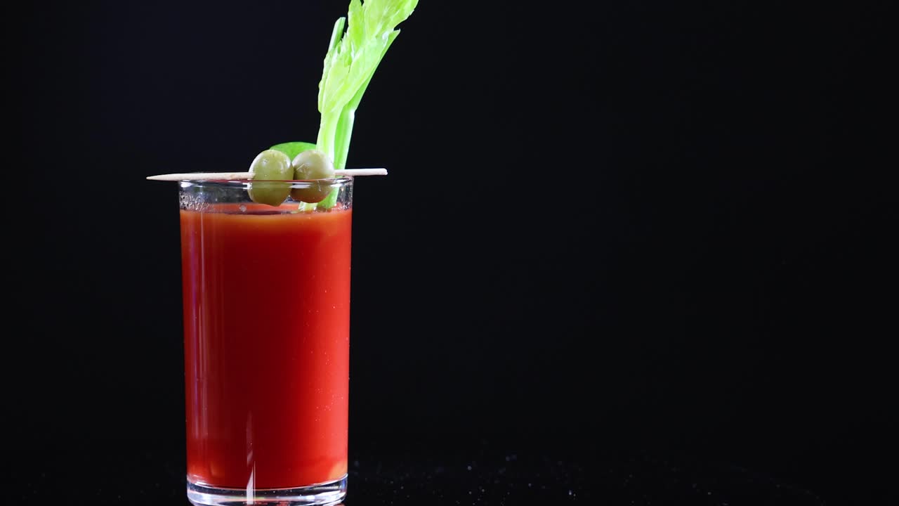 Bloody Mary cocktails with garnishes on a black background, showcasing vibrant colors and minimalistic composition