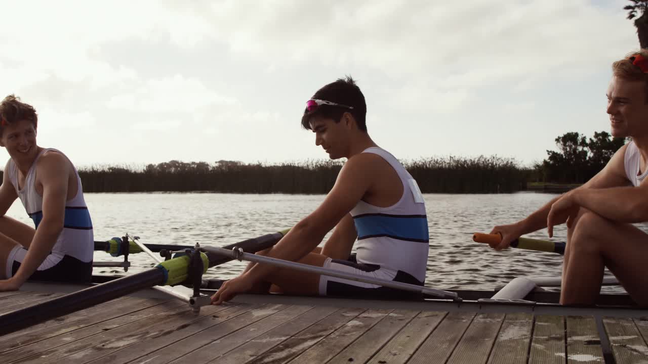 Male rowers laughing on the boat after practice