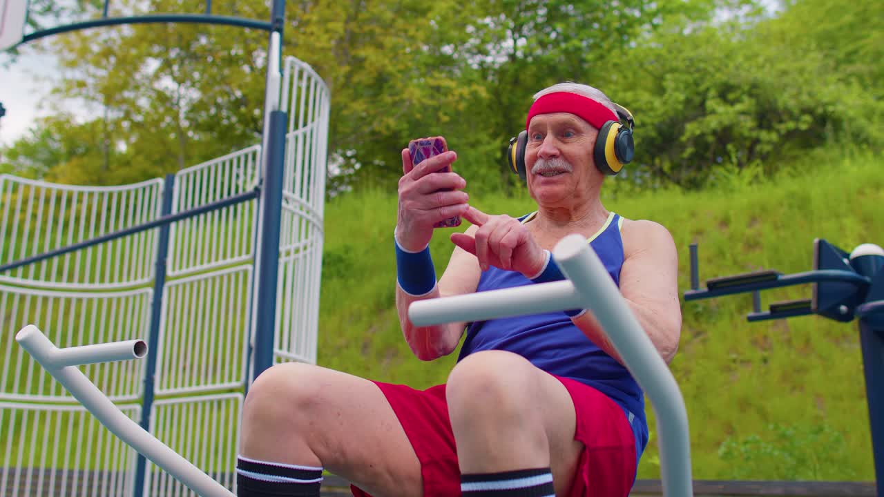 hombre mayor después del entrenamiento deportivo escuchando música en el patio de recreo, celebrando la victoria haciendo el gesto del ganador