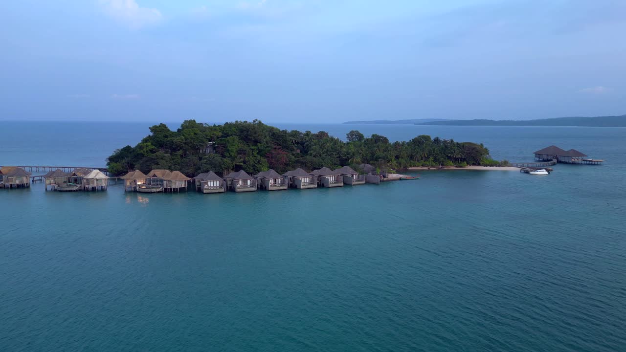 Song Saa Private Island, a luxury resort connecting two islands with a pier and overwater bungalows. Spectacular aerial view flight static tripod hovering drone