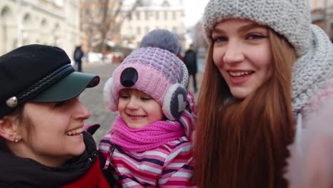 Sisters-tourists-taking-selfie,-posing,-making-video-conferencing-on-mobile-phone-with-child-girl