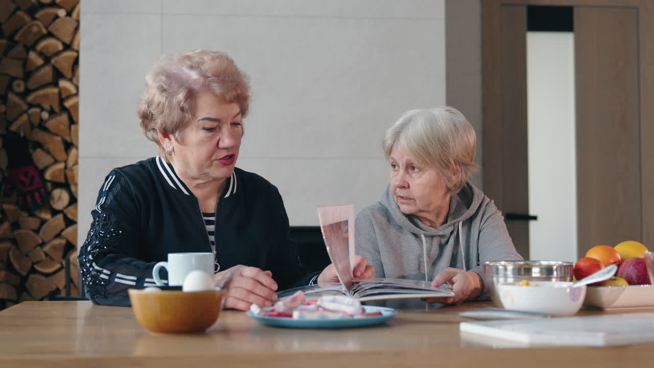 두 명의 고위 여성들이 사진 앨범을 살펴보고 있습니다.