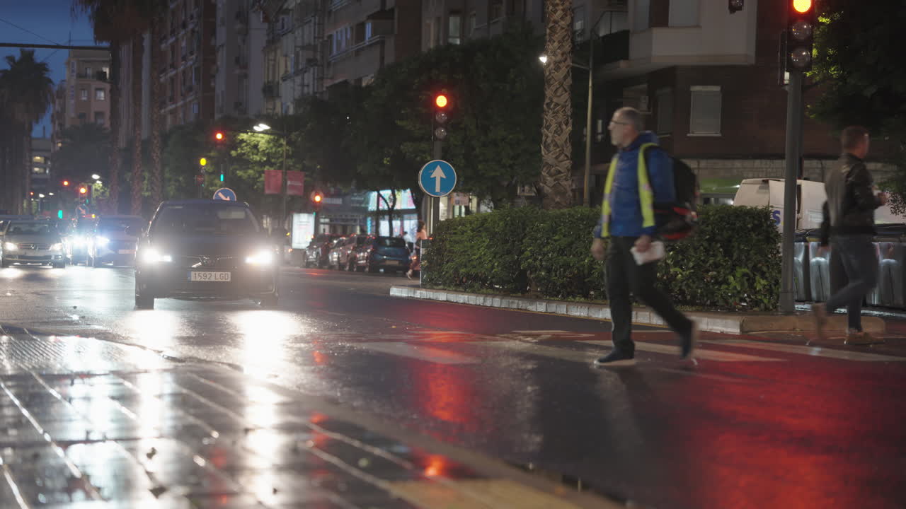 People Crossing a Wet City Street at Night with Traffic Lights