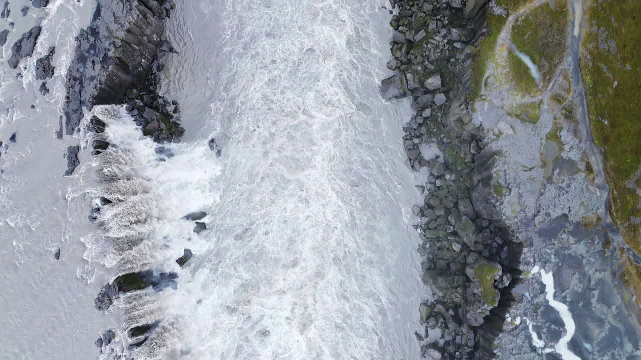 Veduta aerea con drone dell'immensa cortina d'acqua alla cascata di Dettifoss. Le acque turbolente si riversano dal bordo della scogliera in un canyon avvolto nella nebbia
