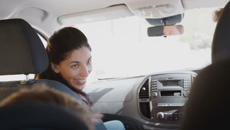 mother talking to children in back seat of car as family drive on family vacation