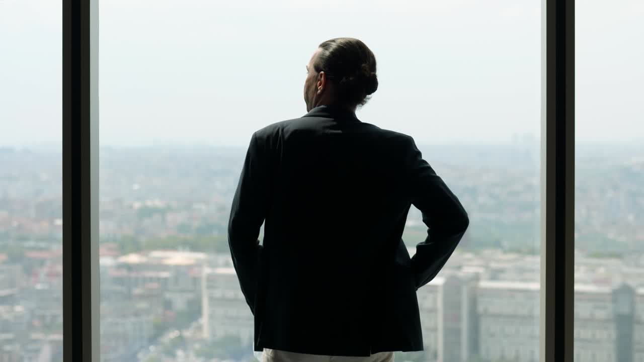 hombre de pie mirando por la ventana a la ciudad, quitando la máscara médica de su cara
