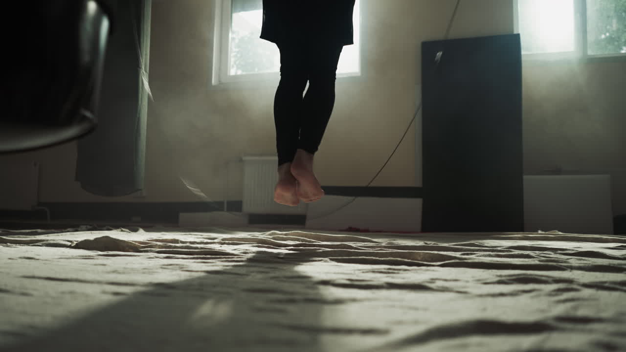 парень прыгает на веревку в боевом тренажерном зале вблизи. боксер делает упражнения с веревкой в клубе боевых искусств в замедленном движении. энергичная тренировка