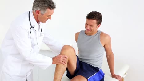 doctor checking sportsmans injured knee