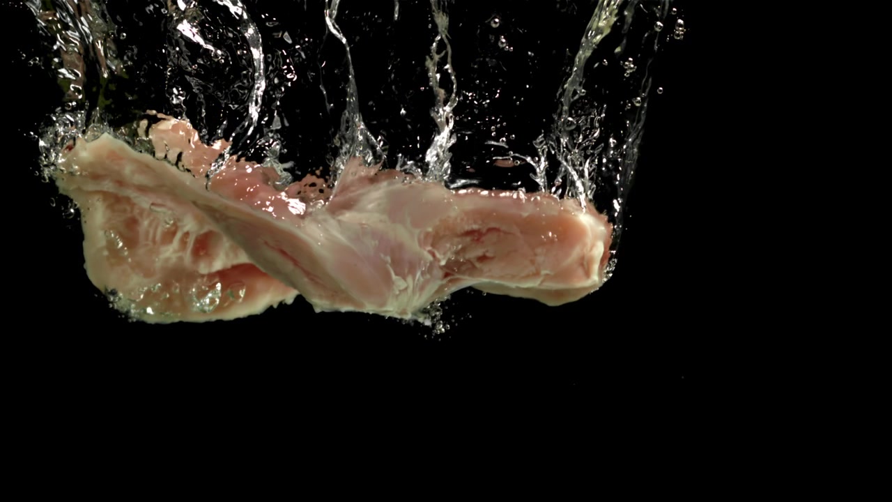 Carne di pollo cruda che cade nell'acqua al rallentatore