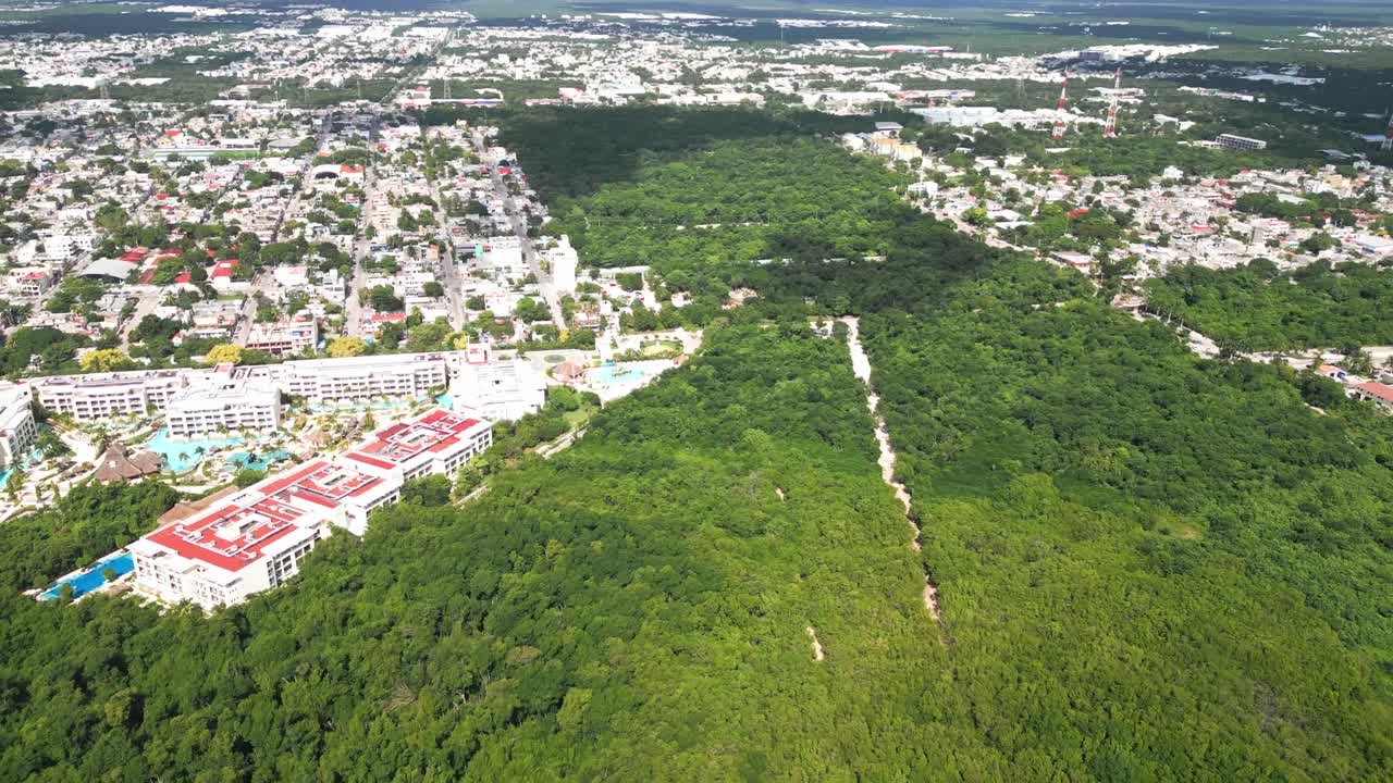 Drone footage above Playa Esmeralda, Mexico, revealing contrast between tropical jungle and resort development, illustrating tourism growth, urbanisation and natural landscape balance
