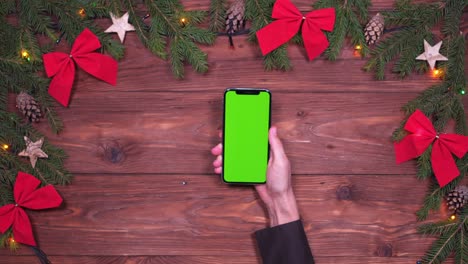 hand placing smartphone on christmas background
