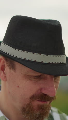 a man in a black hat and a checkered shirt is intensely focused on an unseen task, with mosquitoes visibly flying around his head. his deep concentration creates a serene yet determined atmosphere