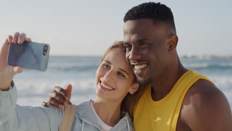 Porträt-Eines-Jungen-Multiethnischen-Paares,-Das-Lächelnd-Ein-Selfie-Foto-Mit-Der-Smartphone-Kamera-Am-Strand-Macht-Und-Gemeinsam-Einen-Romantischen-Urlaub-An-Der-Warmen-Sommerküste-Genießt