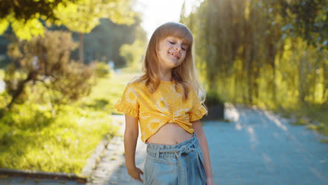 a little girl smiles and waves in a park