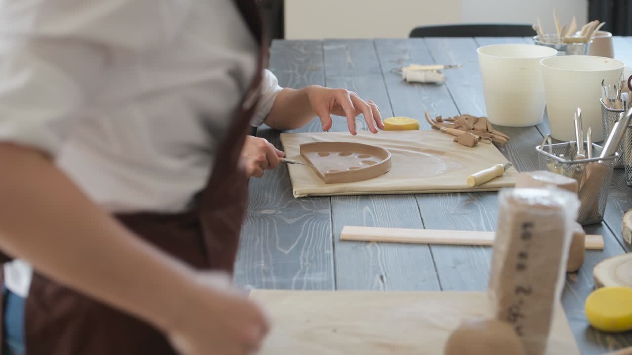 manos femeninas sosteniendo palos y haciendo adornos en productos decorativos. maestro de arcilla moldeando arcilla en un taller de cerámica y cerámica
