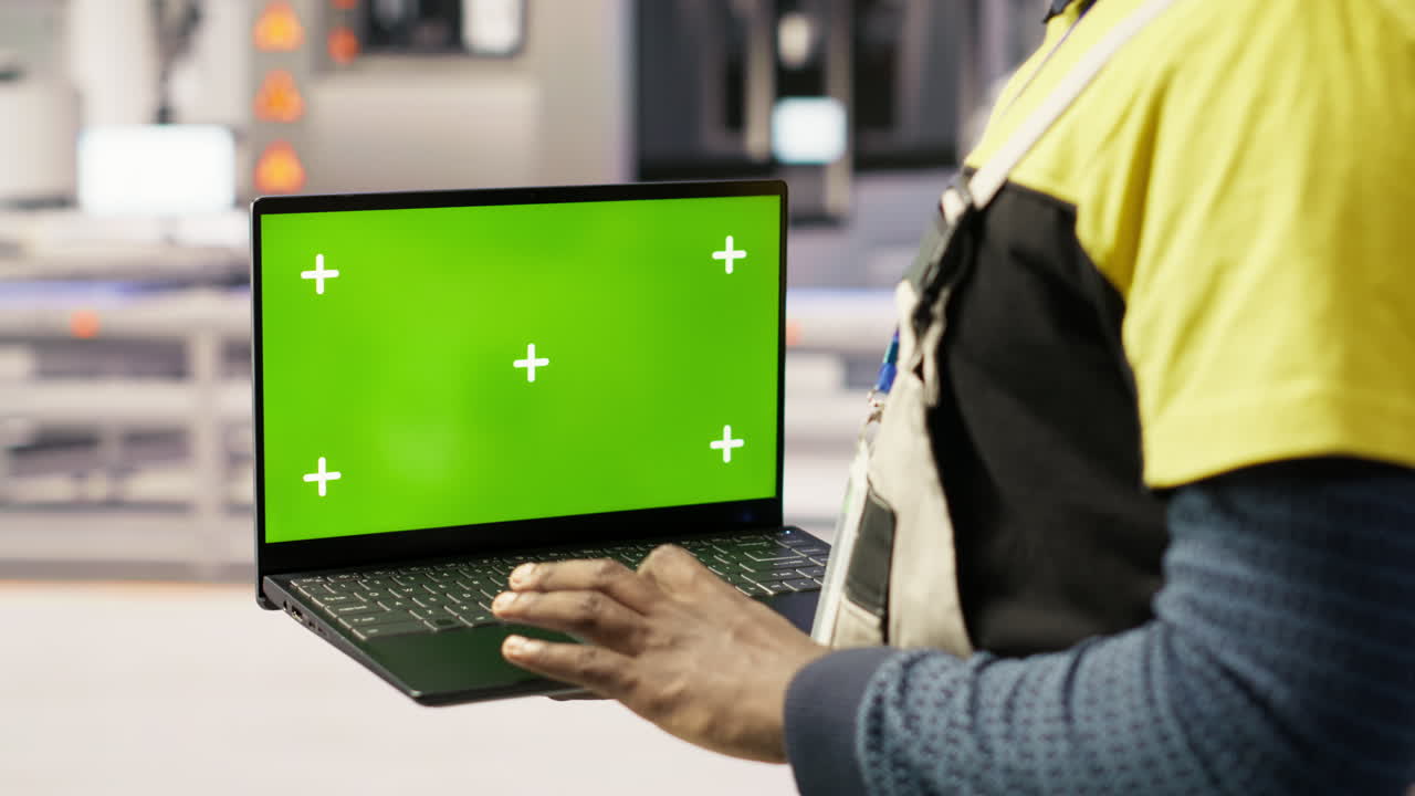 Factory engineer using green screen laptop to calibrate high tech machinery