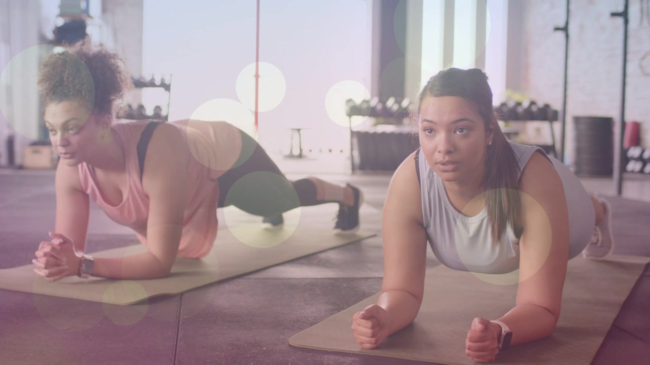 Starting plank two women holding forearm plank on mats in fitness studio maintaining core