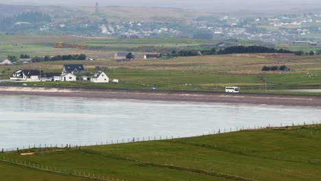 telephoto lens shot of crofts and fields around point as well as the braighe road near stornoway, which is visible in the distance
