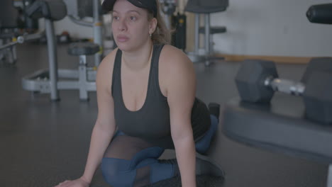 close up tilt up of a woman stretching her legs at a gym