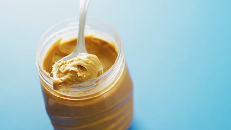 Video-of-close-up-of-peanut-butter-on-blue-background