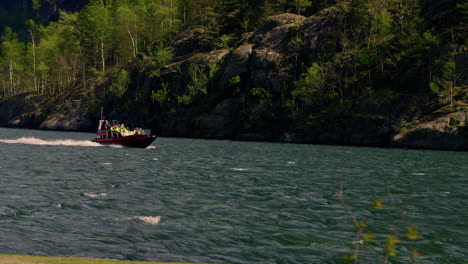 Cinematic-slow-motion-shot-of-a-speed-boat-filled-with-people-in-yellow-life-jackets-driving-on-rough-waters
