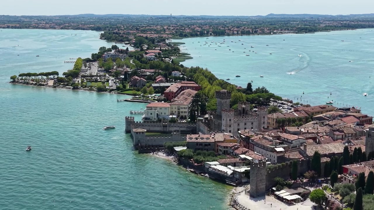 Vista drone del Castello Scaligero di Sirmione che domina la penisola storica circondata dalle acque turchesi del Lago di Garda, Italia.