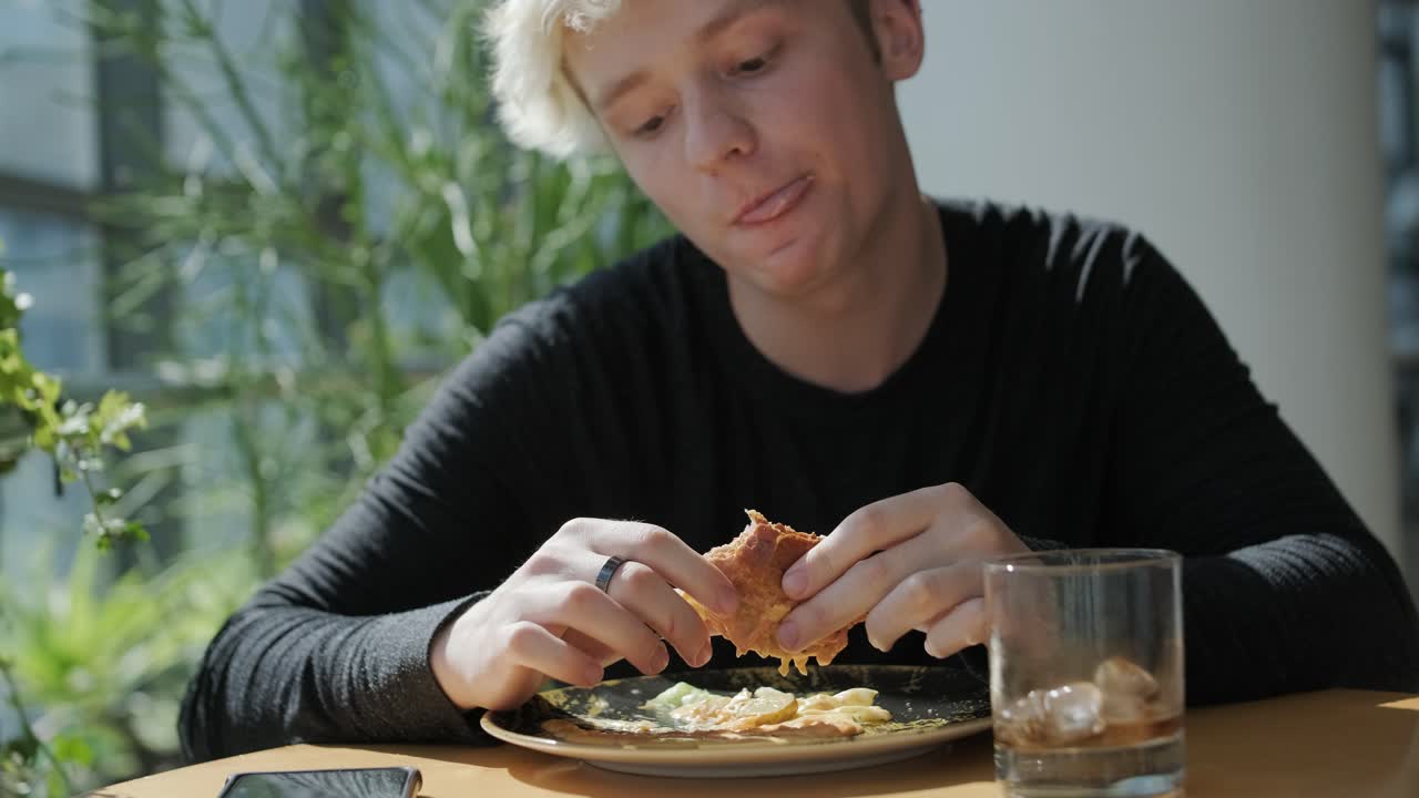 un joven comiendo un sándwich.