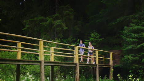 Ein-Paar-Touristen-Gehen-Vorsichtig-über-Eine-Brücke-über-Einen-Bergfluss-4k-Video