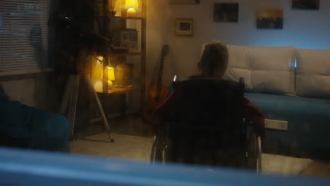 boy in wheelchair in living room at night