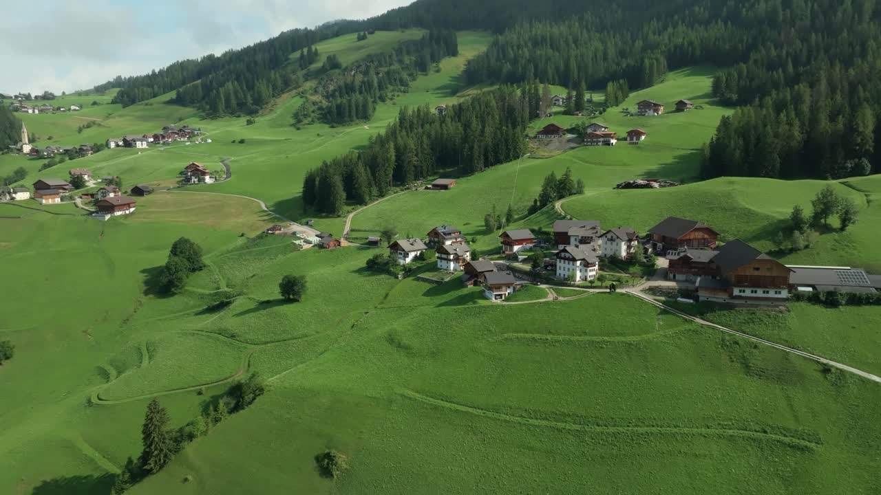 imágenes aéreas de descenso cinematográfico de las pintorescas granjas en las exuberantes colinas verdes de la aldea de la val en los dolomitas italianos
