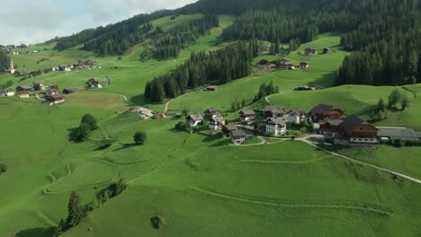 Cinematic-descending-aerial-footage-of-the-picturesque-farm-houses-on-the-lush-green-hills-of-the-La-Val-village-in-the-Italian-Dolomites