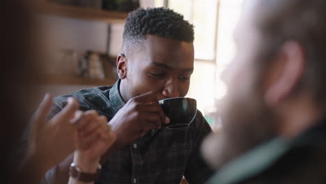 happy-african-american-man-hanging-out-with-friends-in-cafe-chatting-sharing-conversation-drinking-coffee-enjoying-socializing-having-fun-meet-up-in-restaurant