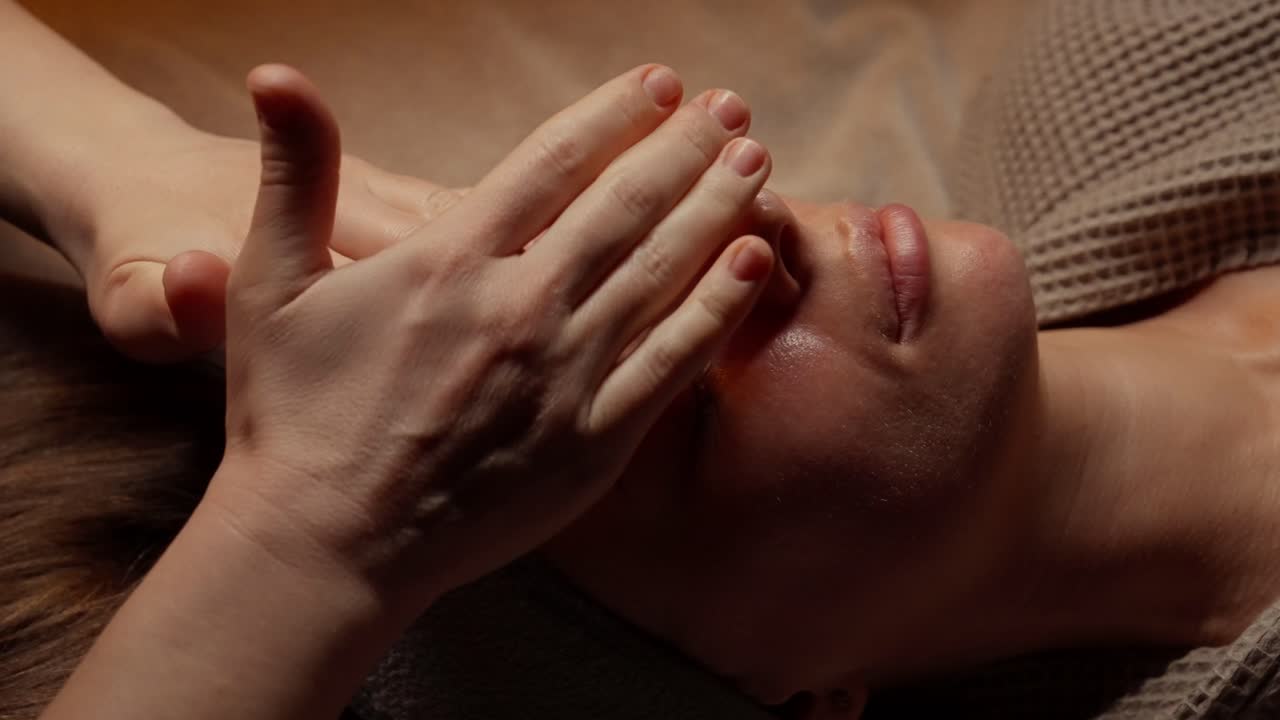 Nærbillede af kvinde, der får afslappende ansigtsmassage på et spa