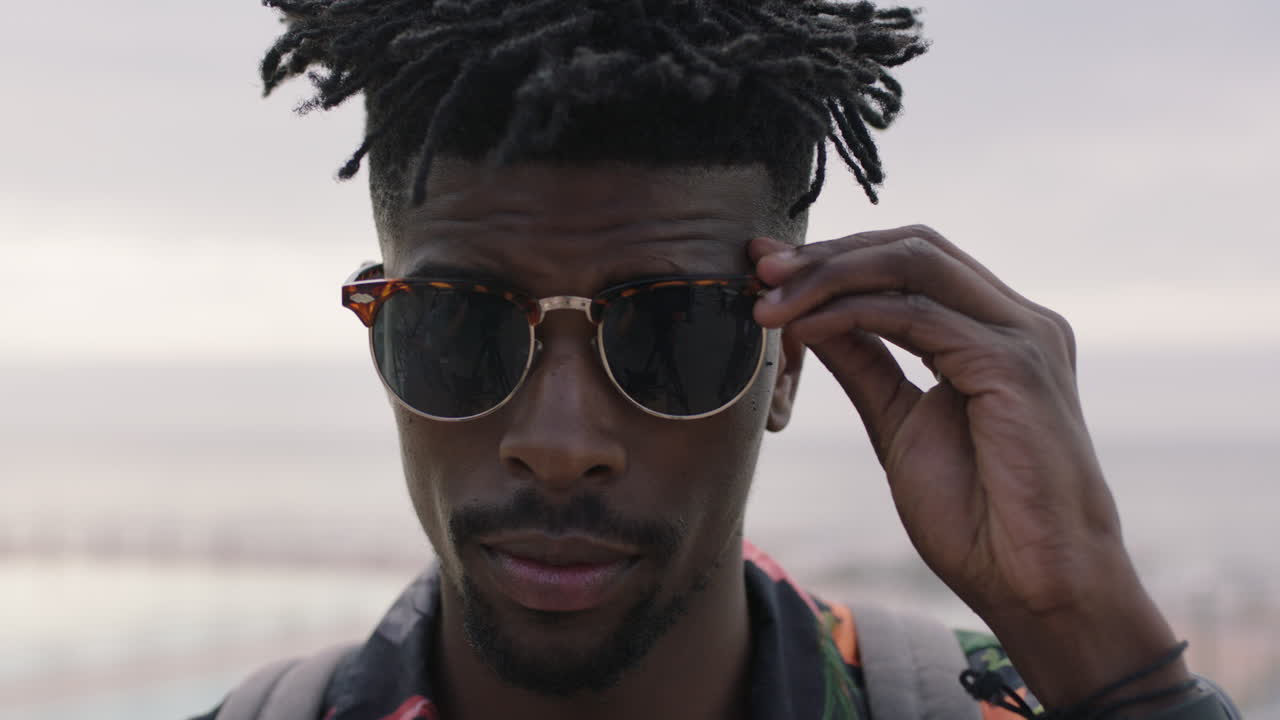 primer plano de un atractivo hombre afroamericano que se pone gafas de sol