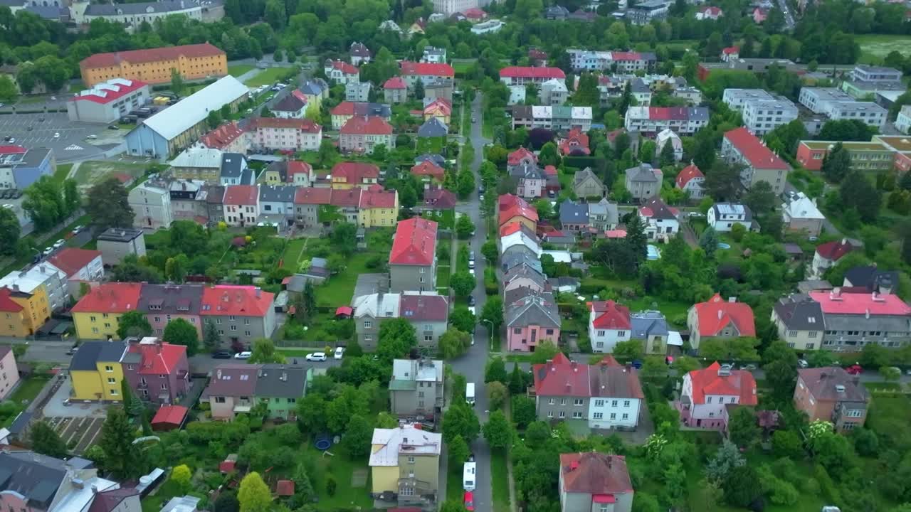 A drone view of a neighborhood in Olomouc, showing houses, streets, greenery, and trees. A blend of urban and natural elements from above.