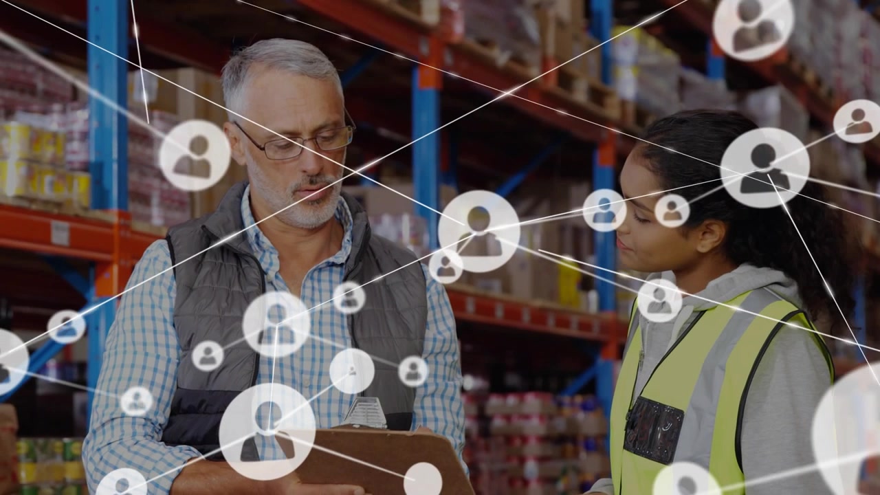 Coworkers checking clipboard in warehouse watching user icons forming network showing connectivity