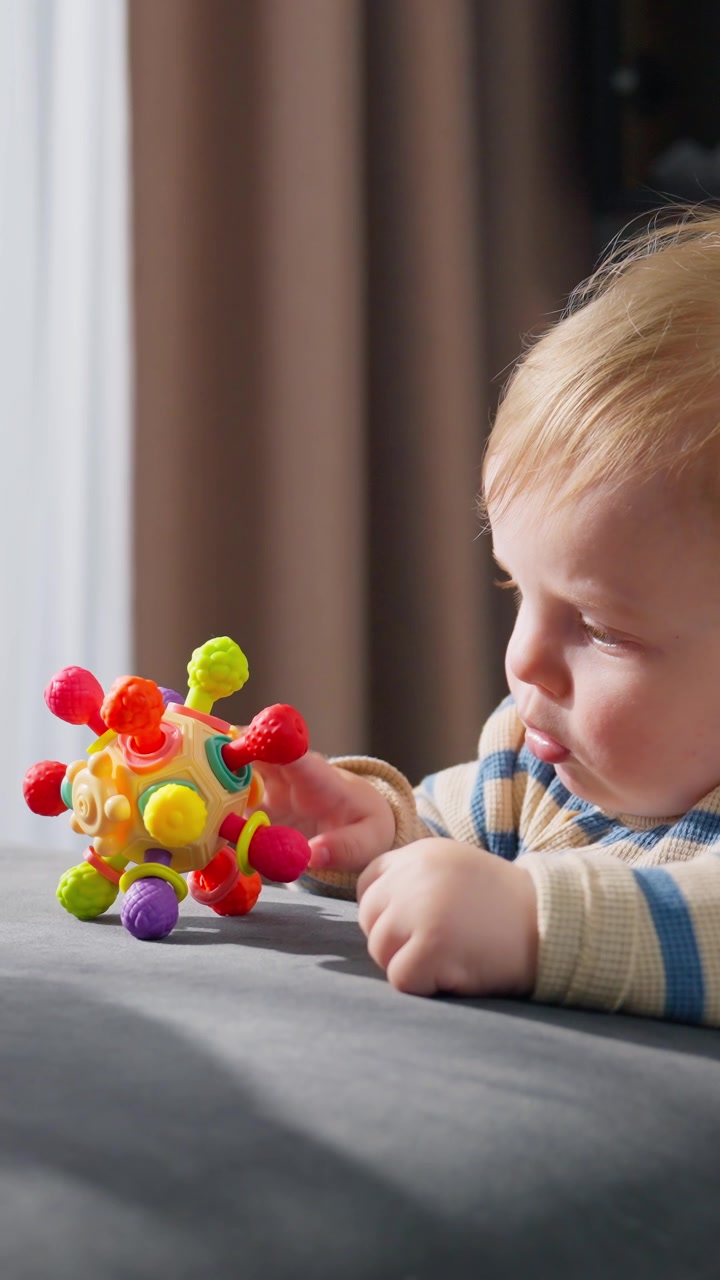 Bambino carino che gioca con un giocattolo sensoriale colorato sul divano.