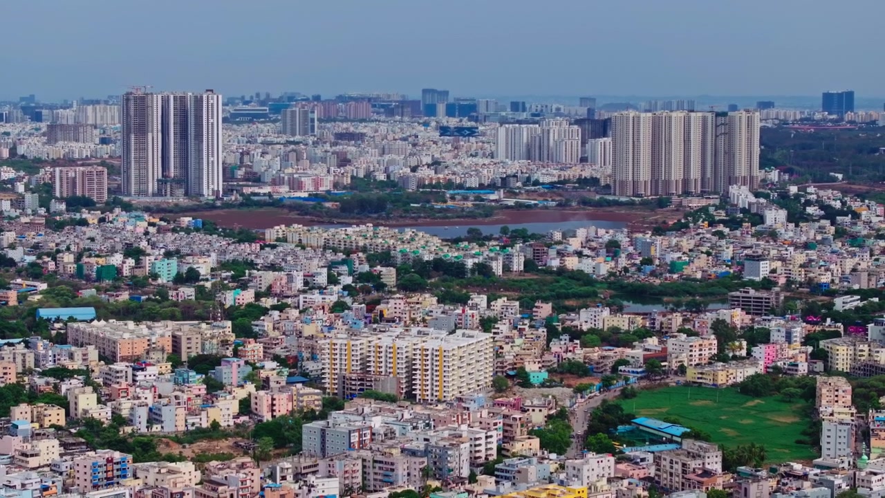Vista aerea degli edifici residenziali di Lingampally con grattacieli e il lago Lingappa Kunta a Hyderabad, Telangana, India. Di giorno, ripresa all'indietro, scatto da drone, 4K.