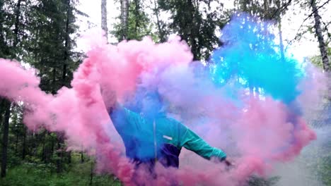 person releasing colorful smoke bombs in a forest