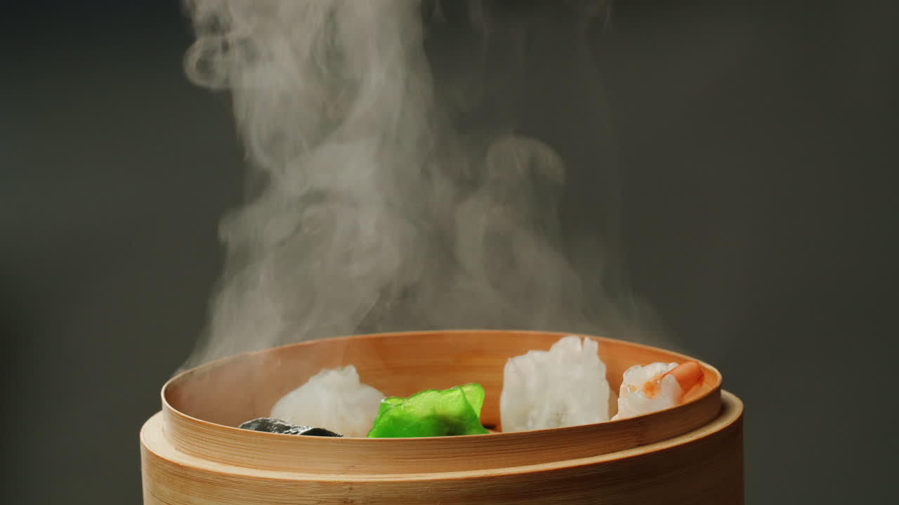 Hand Lifts Lid from Bamboo Steamer Revealing Hot Dim Sum