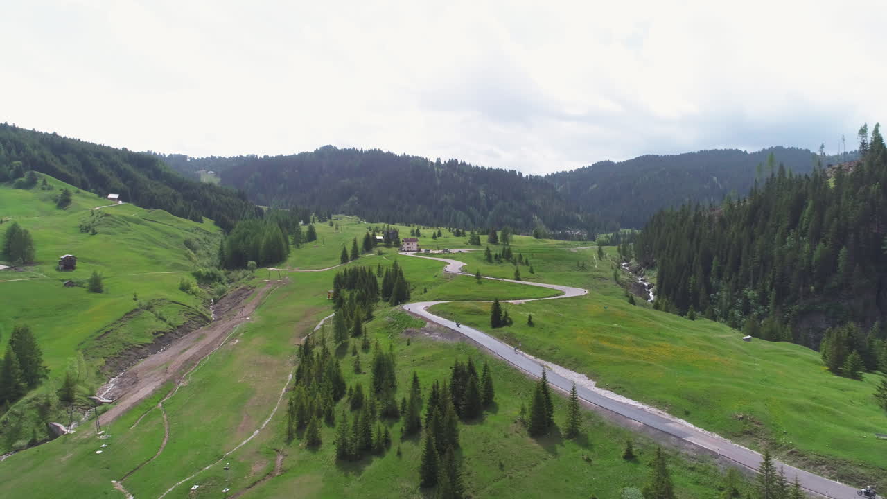 Cyclist Riding on a Road Though a Field in the Dolomites, Italy, from a Drone