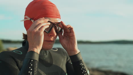 female triathlete putting on swimming goggles