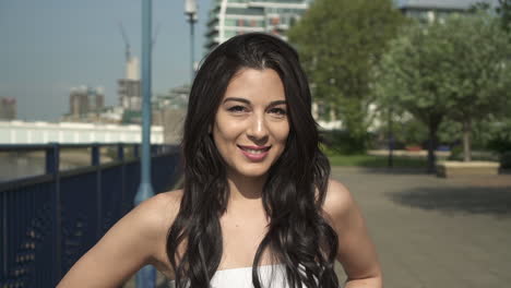 slow motion portrait of a beautiful hispanic latina young woman looking at the camera and show emotions from serious to smiling and laughing