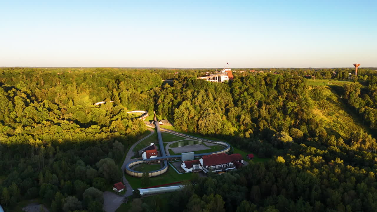 Sigulda, Latvia: Bobsleigh, Luge, And Skeleton Track Nestled In The Beautiful And Scenic Gauja Valley Forest Landscape. 4K Aerial, Establishing Location.