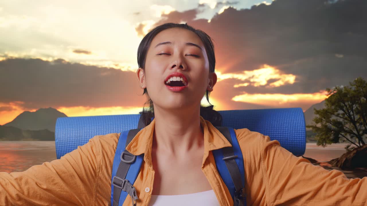 Close Up Of Asian Female Hiker With Mountaineering Backpack Smiling And Spreading Arms Enjoy Looking The View Around While Standing At A Lake During Sunset Time