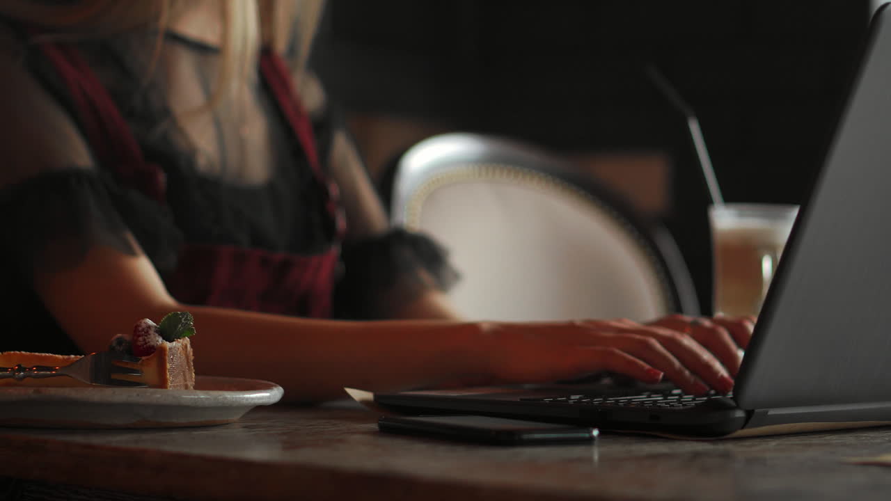 Young woman wearing smartwatch using laptop computer. Female working on laptop in an outdoor cafe.