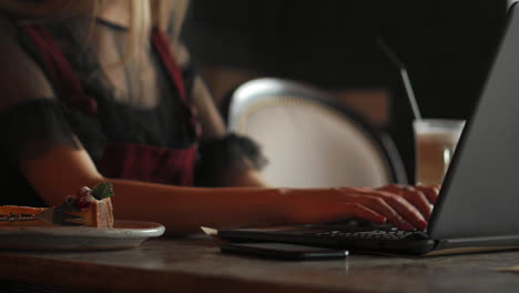 Young-woman-wearing-smartwatch-using-laptop-computer.-Female-working-on-laptop-in-an-outdoor-cafe.