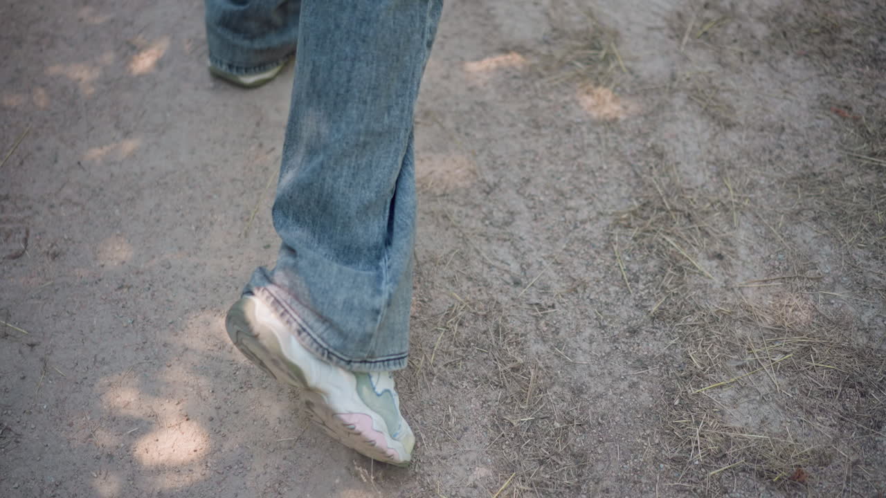 primer plano de una pisada sobre tela vaquera en un sendero, luz suave al atardecer, ritmo tranquilo, patrones de sombras, ambiente meditativo, sendero en un parque, brisa suave, suela de zapatilla desgastada, viaje introspectivo, atmósfera tranquila