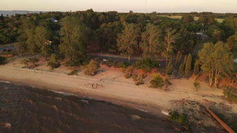 Eine-Dynamische-Luftaufnahme-Einer-Gruppe-Von-Freunden,-Die-Beachvolleyball-Spielen,-Vom-Meer-Aus